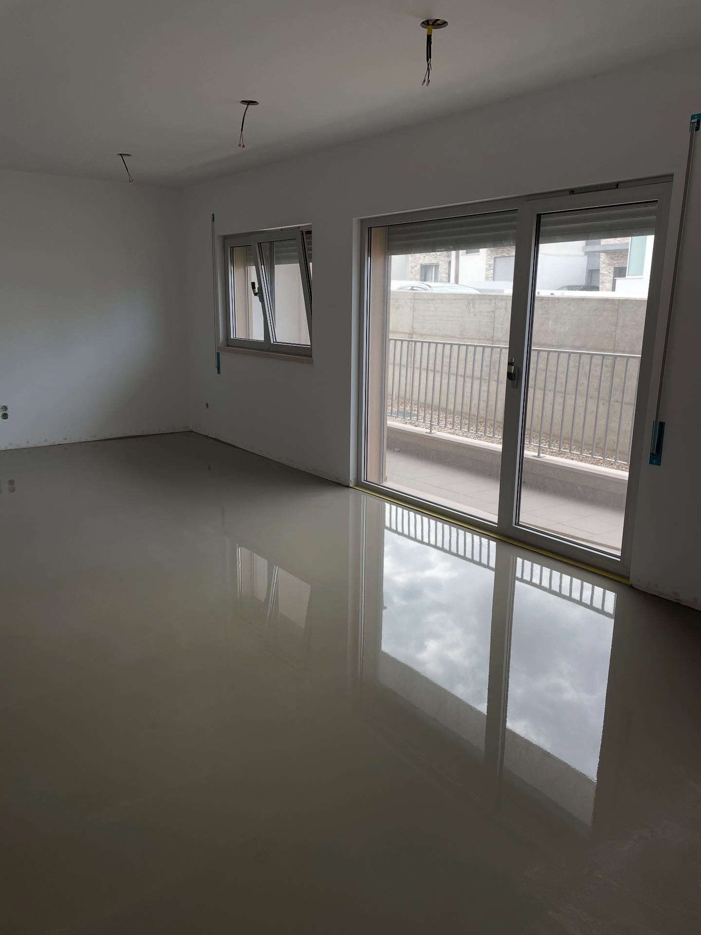 Sala com pavimento autonivelante cimentício a reflectir a porta de vidro